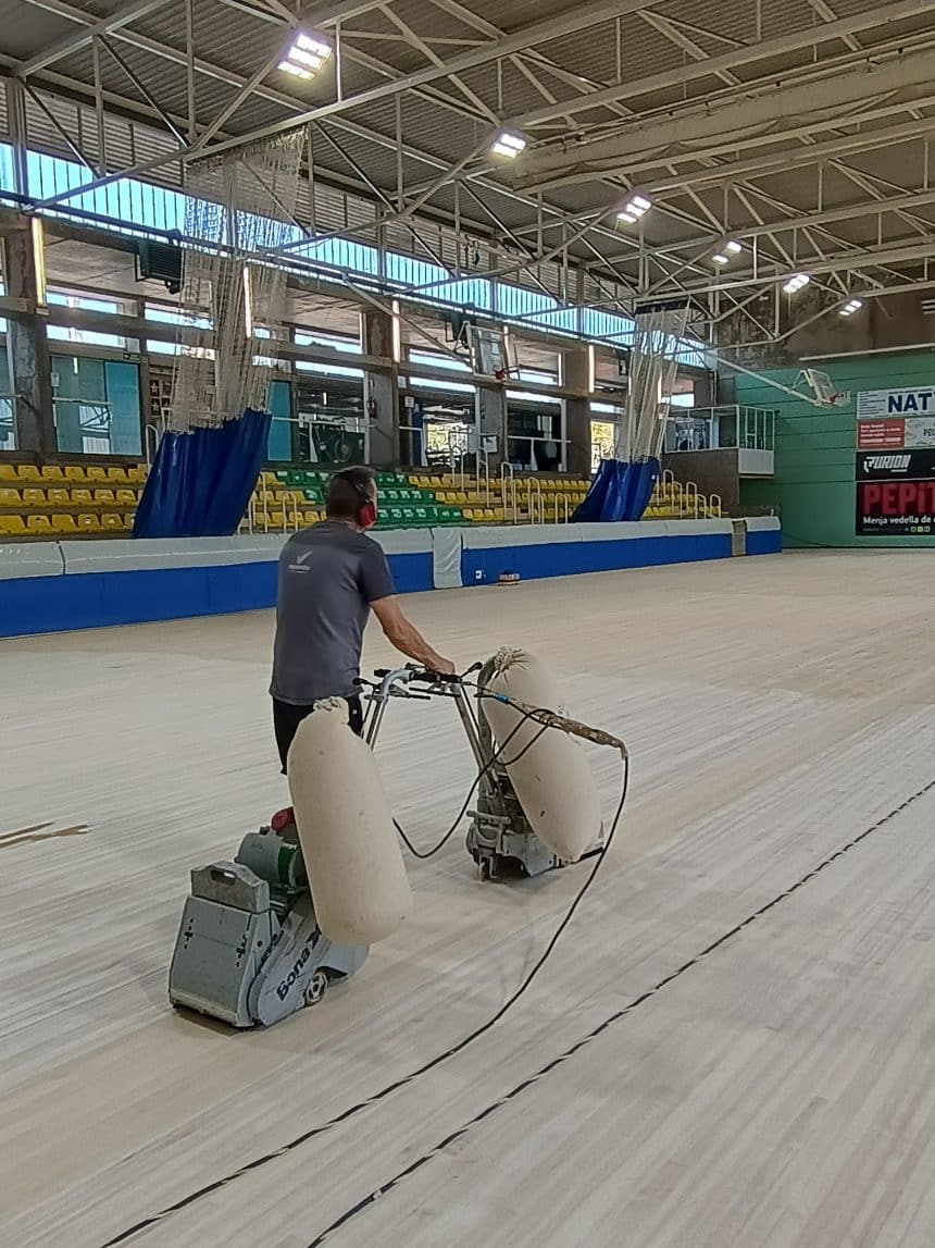 Operari polint el parquet de la pista interior d’un pavelló esportiu